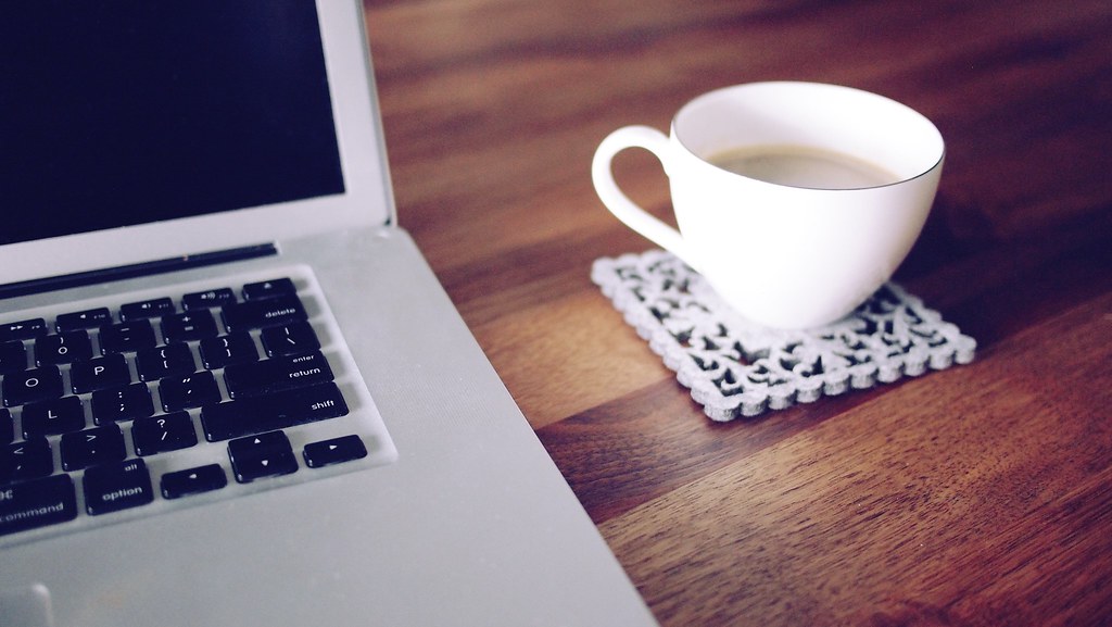 Laptop and coffee on a wooden desk, used as the page's main hero image
